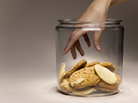 Woman reaching for cookies in cookie jar, close-up of hand