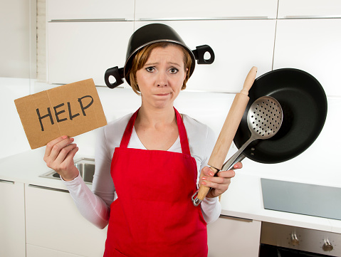 woman in the kitchen cooking holding a help sign