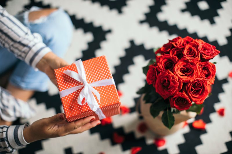 Woman holding Valentine's Day gift next to roses