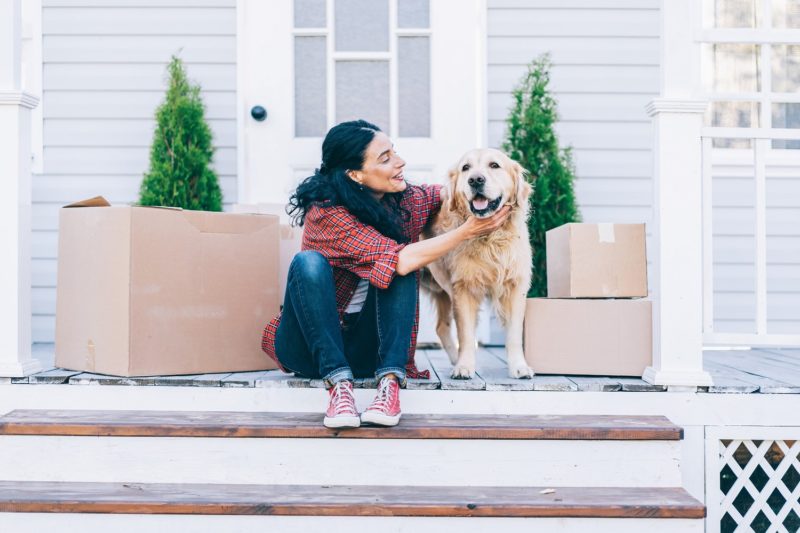 a woman and a dog sitting on a porch with boxes of food