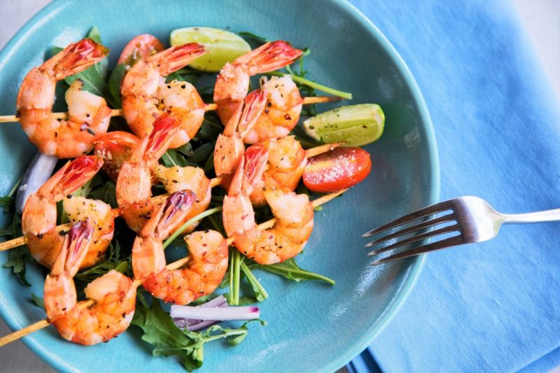 Grilled shrimp skewers with salad and lime slices