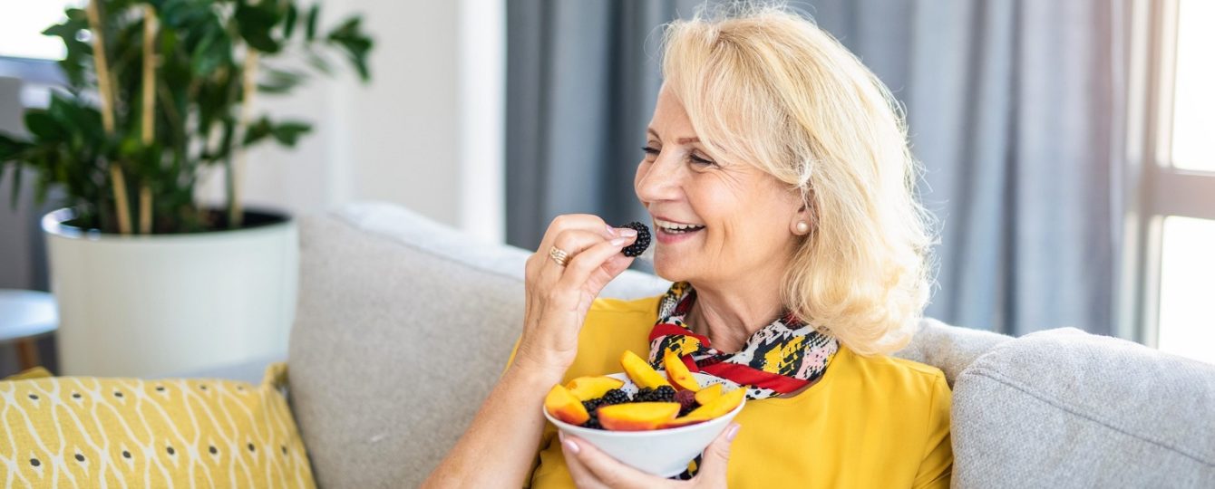 woman eating healthy berries and fruit on a couch
