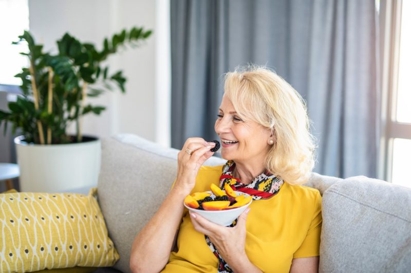 woman eating healthy berries and fruit on a couch