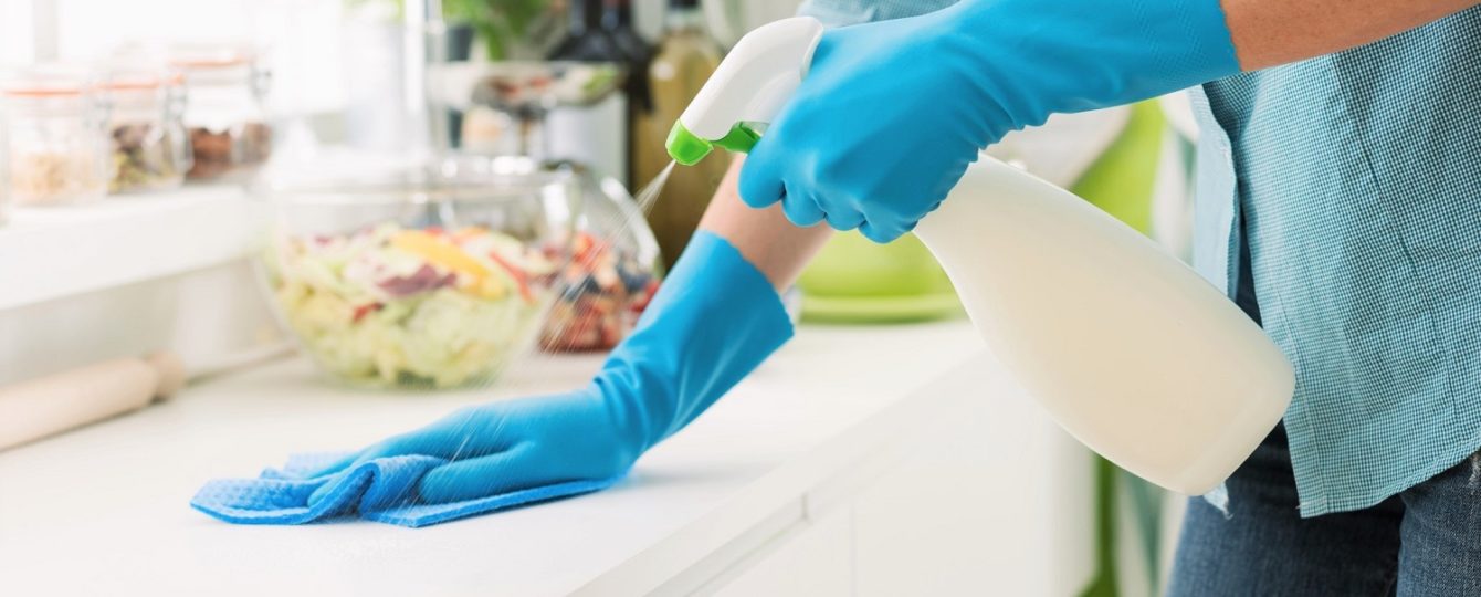 Woman cleaning and polishing the kitchen worktop with a spray detergent