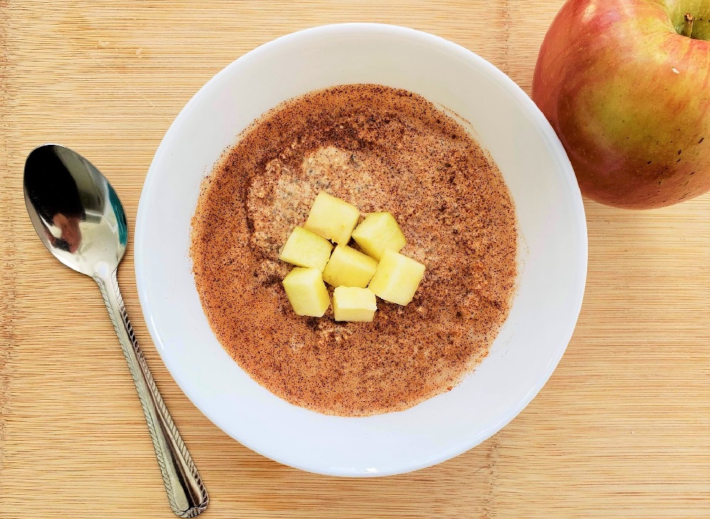 Apple and Cinnamon Blended Overnight Oats with chopped apples and a spoon in a white bowl