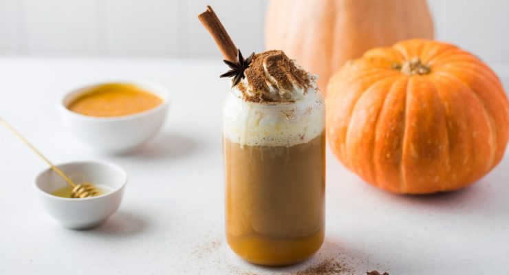 Pumpkin coffee with whipped cream and spices on table