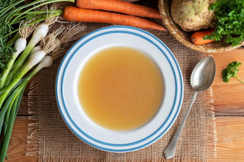 Chicken bone broth in a plate with vegetables